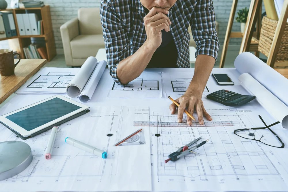 Profissional revisando uma prancha impressa com plantas de uma edificação